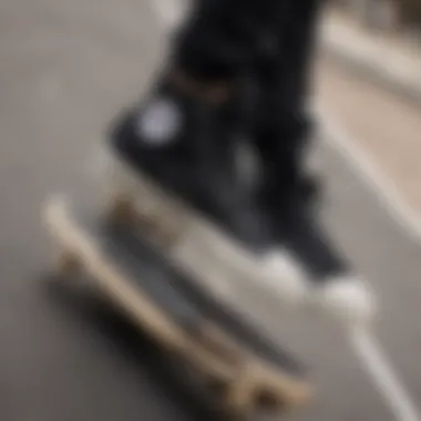 A pair of all black Converse high tops on a skateboard at an urban skatepark.